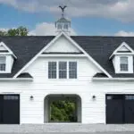 A white two story garage with black doors.