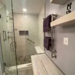 A bathroom with a bench and shower stall.