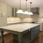 A kitchen with white cabinets and wooden floors.