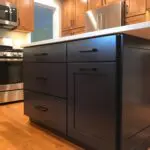 A kitchen with wood floors and black cabinets.