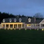 A large white house with lights on the front lawn.